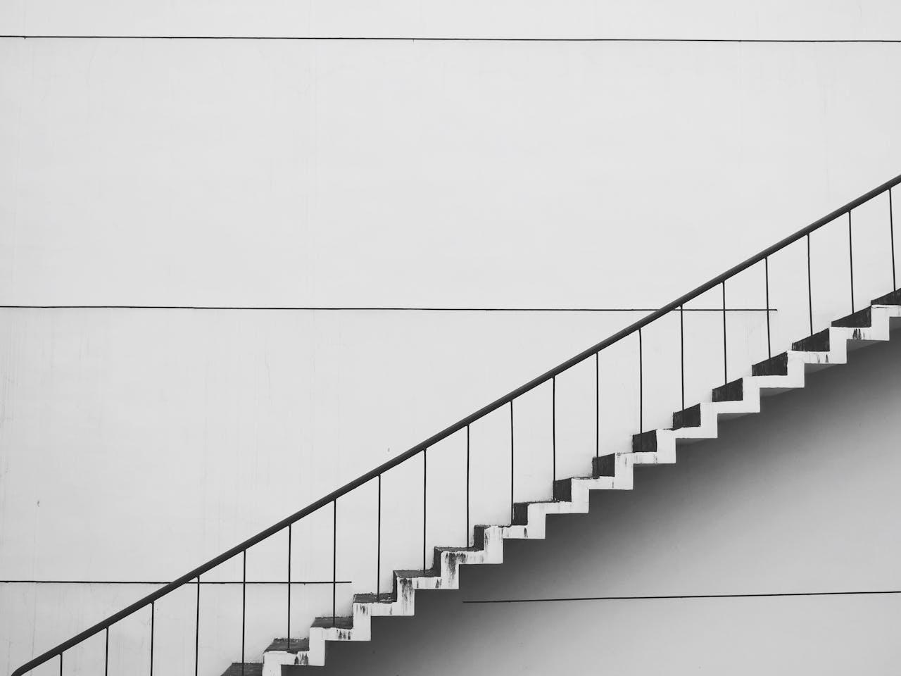 Schwarz-Weiss-Foto einer diagonalen Aussentreppe vor einer weissen Wand.