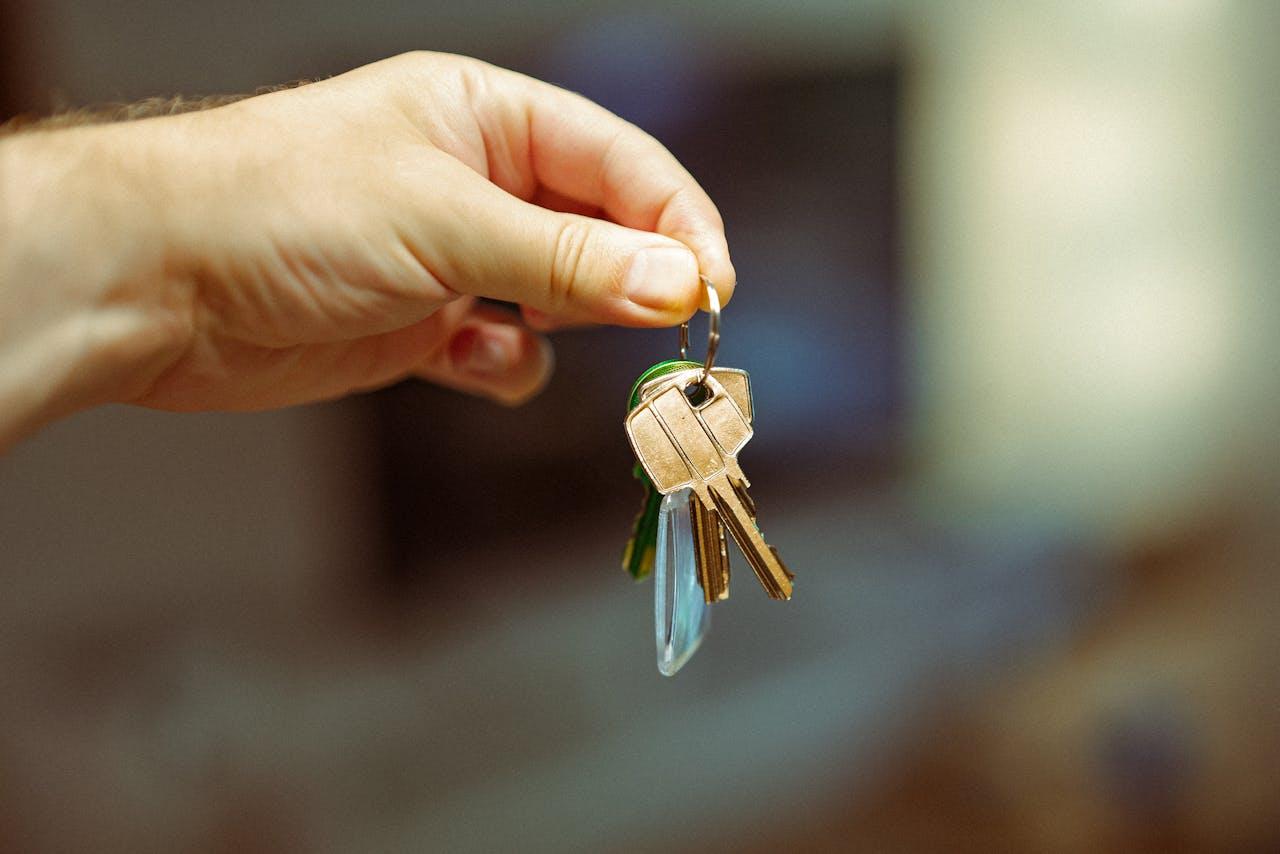 Main tenant un porte-clés avec plusieurs clés dorées sur un fond flou