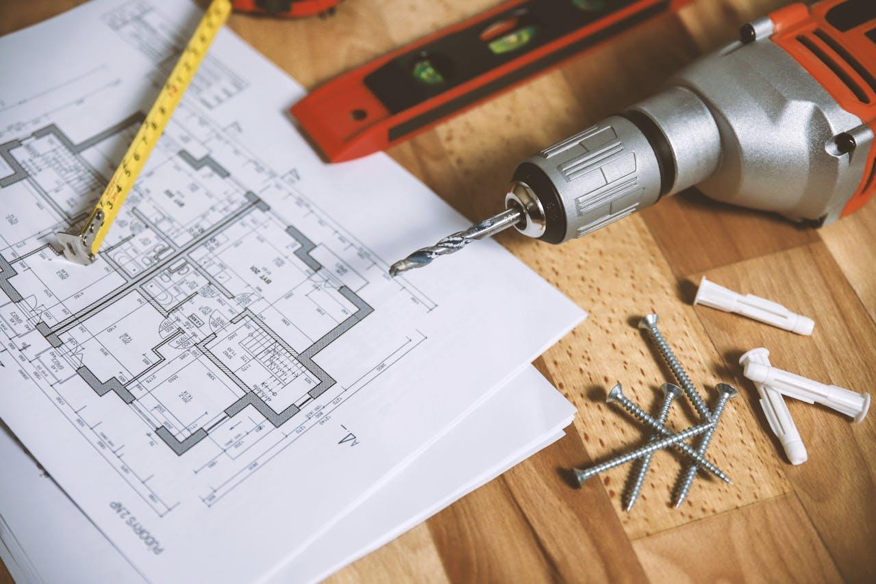 Plan de construction sur table en bois avec perceuse, ruban à mesurer, vis et chevilles