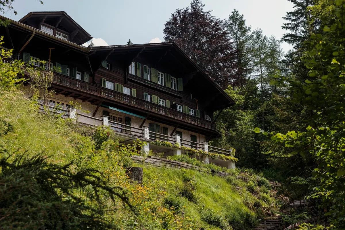 Chalet historique sur une pente verdoyante.