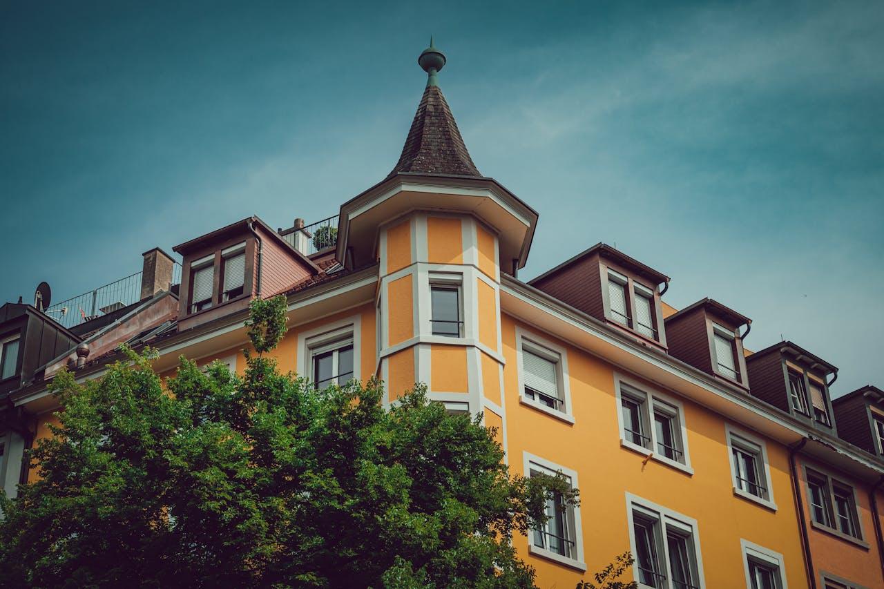 Altbau mit Turmerker in kräftigem Gelb.