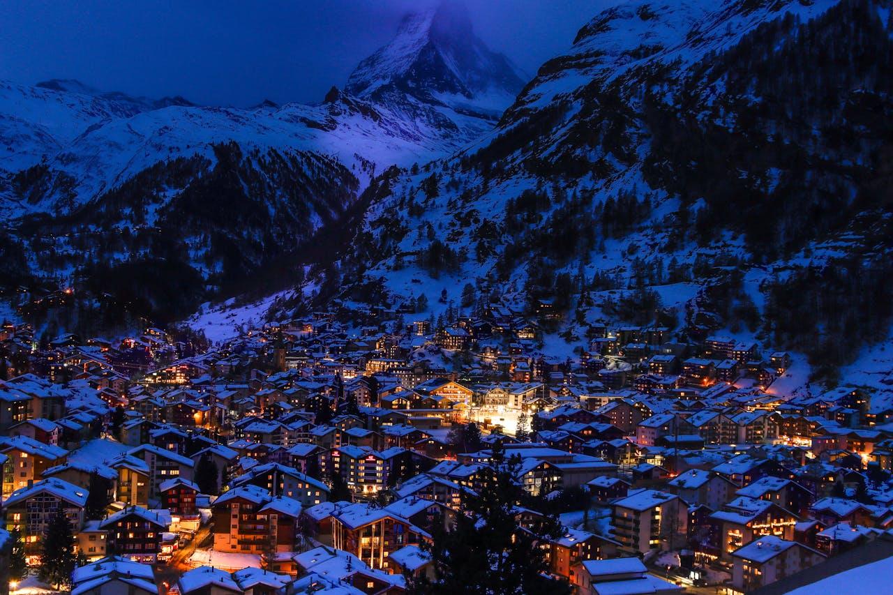 Montagne innevate, villaggio illuminato.